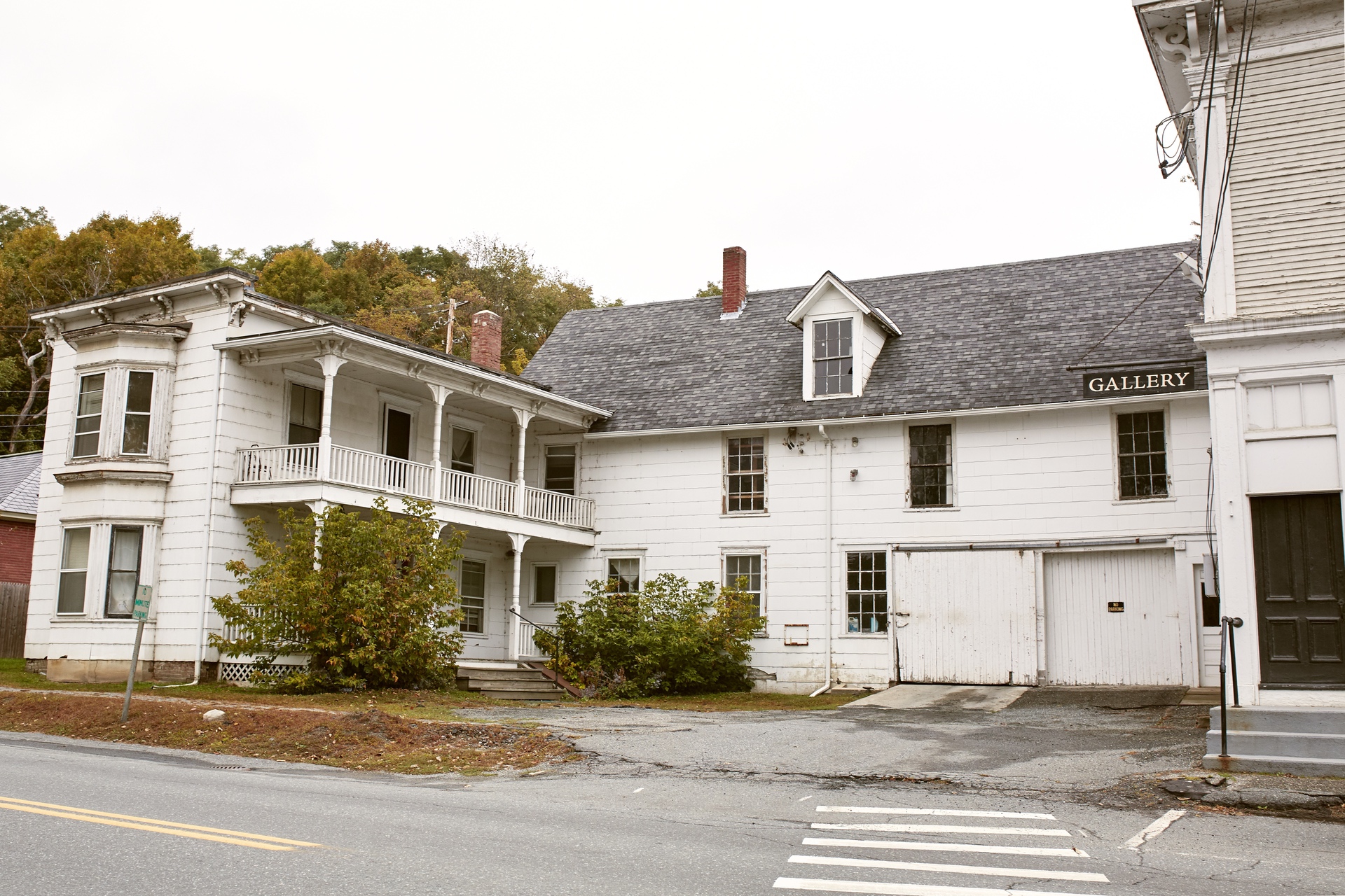 White 2-story older home apartment with second-story porch on cool fall day in Quechee, VT